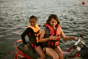 Mother and daughter smiling while riding a jetski on the lake.