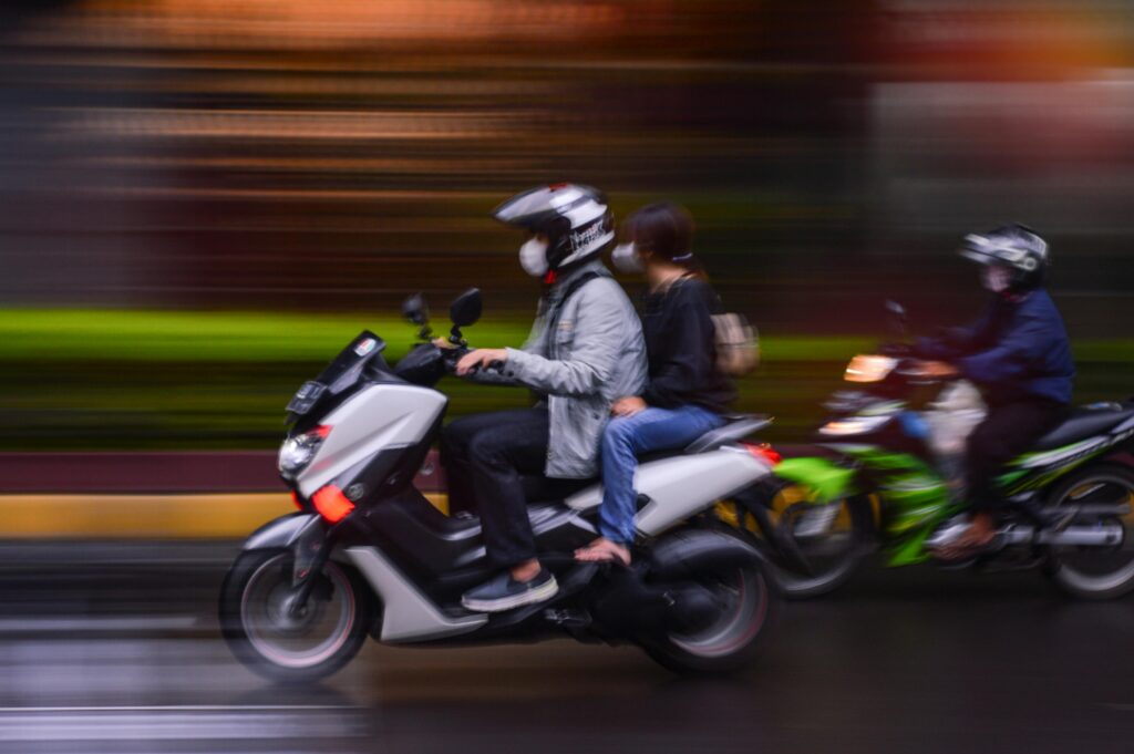 pexels-photo-14199426-14199426 Blurred motion capture of people on scooters rushing through city streets, evoking urban mobility.