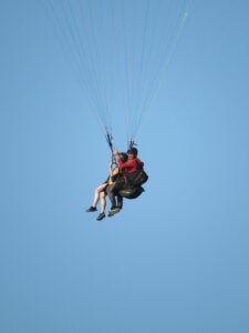 Enjoy the thrill of tandem paragliding against a clear blue sky, perfect for adventure seekers.