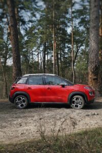 A red car parked in a natural forest area near Kyiv, Ukraine.